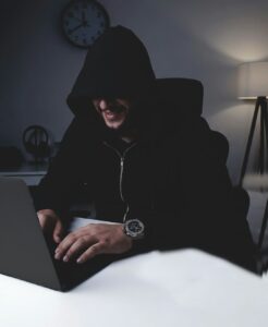 Person reviewing a suspicious email beside a laptop and disconnected backup drive on a home office desk